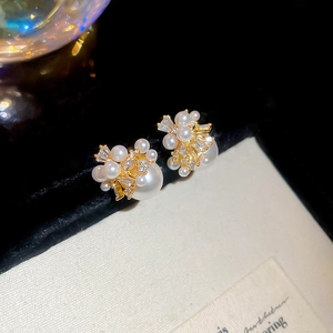 Macro view of gold-plated pearl earrings with sparkling zircon accents on black velvet
