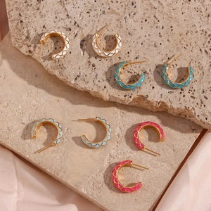 Detail of colorful enamel grid C-shaped earrings in gold-tone finish on stone background