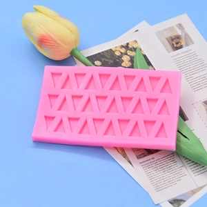 Pink 21-cavity triangle silicone mold for chocolate and DIY baking on blue background