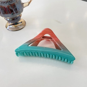 Detail of large triangular hair claw clip with smooth blue to orange gradient resin finish