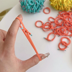 Elastic orange-pink hair ties for girls shown in a durable stretch-test on white background