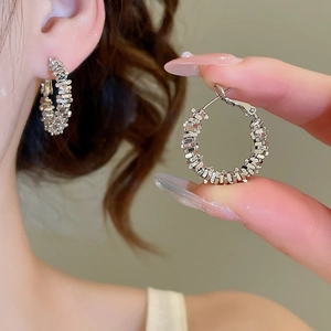 Macro shot of silver woven texture hoop earrings showing detailed metallic pattern