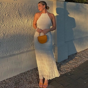 Detail of white backless maxi dress with textured pleated fabric and halter neckline