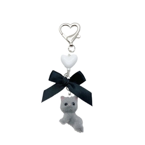 Cute grey flocked kitten keychain with black ribbon bow and silver heart clip on white background