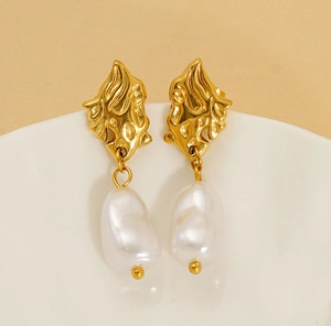 Detailed macro shot of French retro gold earrings with irregular lava texture and white baroque pearl