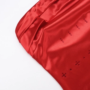 Close-up of red satin bodycon dress showing glossy fabric and rhinestone details