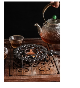 Détail d'un chauffe-théière vintage en fonte avec des motifs sculptés et évidés