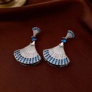 Detailed view of silver fan earrings with zircon and blue stones on velvet background