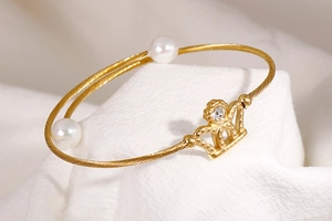 Macro view of gold crown pearl bracelet featuring twisted metal band and sparkling crystal