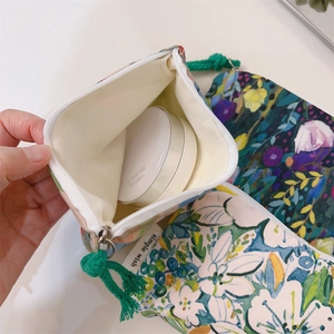 Macro view of floral canvas pouch interior with cream cushion and green zip puller