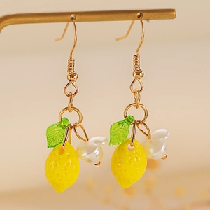 Macro detail of lemon drop earrings with green leaves and white petals on a gold stand