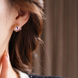Close-up of 18k gold plated pink zircon stud earrings worn by a female model