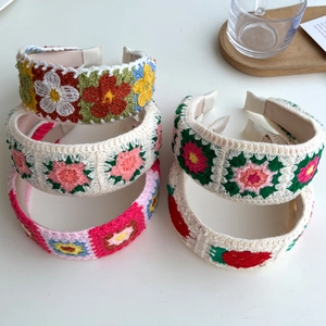 Close-up of four colorful handmade crochet knit floral headbands stacked on a tray