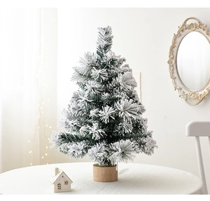 Close-up of small flocked cedar Christmas tree with snow effect on wooden base