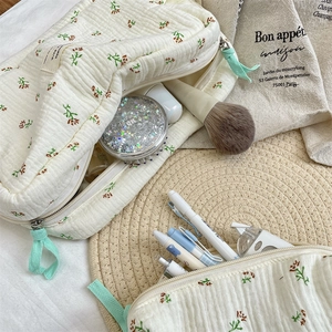 Detail of quilted cotton makeup bag with blue begonia floral pattern and green zipper pull