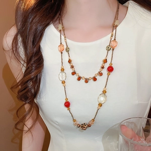 Détail d'un collier long à deux rangs avec perles de résine rouges et ambrées