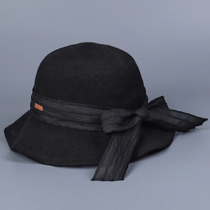 Detailed view of the black knit sun hat featuring a striped ribbon and large bow design