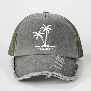Close-up of coconut tree embroidery and distressed brim details on a trucker cap