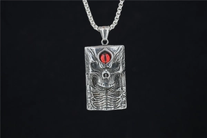 Macro shot of silver gothic skull pendant with a striking red eye on black background