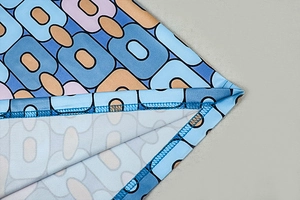 Macro view of geometric pattern dress fabric showing high-quality overlock stitching