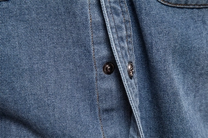 Vue détaillée du tissu denim avec bouton-pression en métal et coutures renforcées