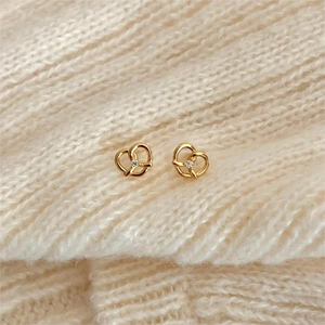 925 silver golden knot stud earrings with white zircon on a beige knit sweater
