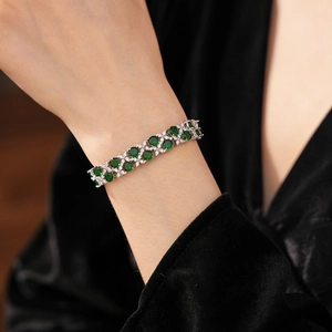 Detail eines smaragdgrünen zweireihigen Blumenarmbands am Handgelenk mit schwarzem Samt