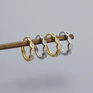 Macro shot of gold and silver S925 huggie earrings with drop-shaped zircon inlays