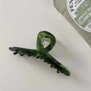 Detailed top view of a translucent green marbled acetate hair claw clip on white background