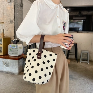 Detail of vintage polka dot canvas tote bag featuring premium leather handles and rivets