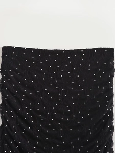 Gros plan sur le tissu plissé noir avec strass étincelants et paillettes délicates