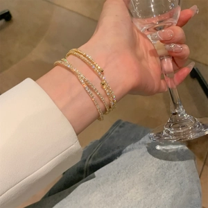 Dettaglio macro di un bracciale a spirale dorato con zirconi lucenti al polso
