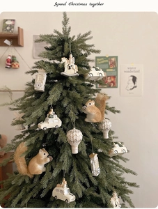 Detail of Christmas tree ornaments featuring furry squirrels and vintage beige cars