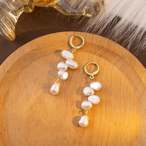 Detailed view of French vintage irregular pearl tassel earrings on a wooden tray