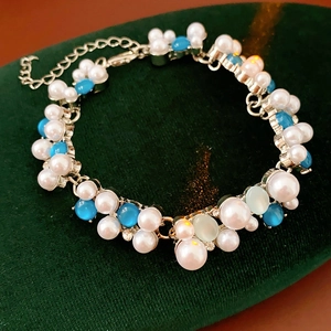 Dettaglio di bracciale vintage multifilo con perle blu, bianche e strass luccicanti
