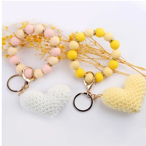 Detail of DIY beaded heart bracelets with pink and yellow knitted charms and metal clasps