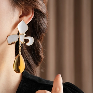 Detail von Vintage-Blumenohrringen mit goldenem Tropfenanhänger an einem Modell