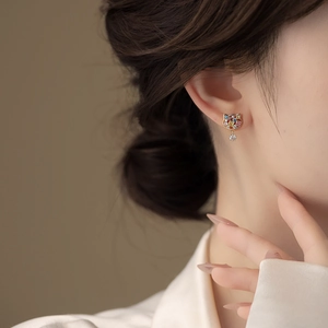 Detailed view of gold plated cat stud earrings with colorful stones and snowflake charms