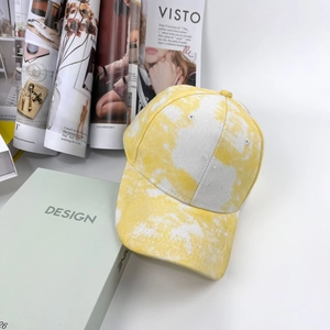 Gros plan d'une casquette en coton tie-dye jaune et blanc près de magazines de mode