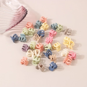 Mini matte flower hair claws in macaron colors scattered on a beige background