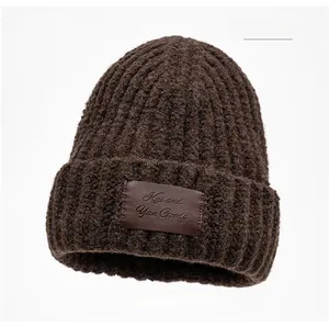 Detail of chunky knit texture and leather brand label on coffee brown beanie hat