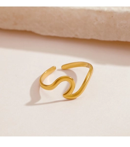 Close-up of minimalist wave-shaped golden stainless steel ring on elegant stone background
