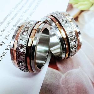 Macro shot of tricolor rotating stainless steel rings with LOVE engraving and small stones