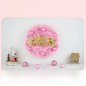 Close-up of pink Christmas wreath with shiny ornaments and Merry Christmas sign