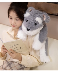 Close-up of a large grey and white plush schnauzer toy held by a woman in a cozy setting