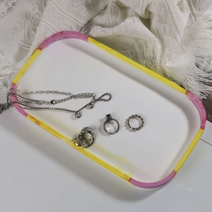 Detailed shot of silver rings and chain jewelry displayed on a glossy oval resin tray