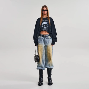 Detail of street style black skull cotton long sleeve top paired with distressed denim jeans