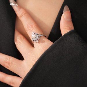 Detail of elegant pearl ring with silver lace design and sparkling zircon accents