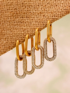 Détail macro de boucles d'oreilles ovales dorées avec zircons sertis sur tissu brut