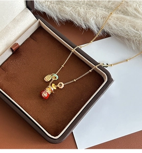 Detailed view of 18k gold plated necklace with red enamel pendants on velvet jewelry box